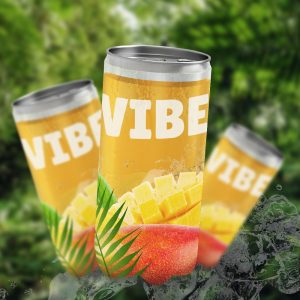 Trois canettes de boisson VIBE jaune, avec de la mangue et des feuilles de palmier, sur fond de végétation verte. Les canettes portent l'inscription VIBE en gros caractères blancs et sont présentées comme un produit d'été, un peu comme une publicité.